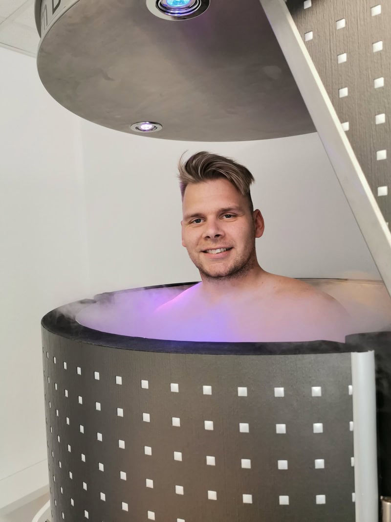 Ein lächelnder Mann in einer Kryokammer mit silbernem Haar und einem modernen Design.