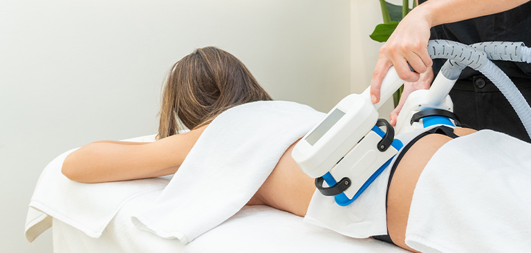 Person erhält eine Behandlung mit einem weißen Gerät auf einem Rücken, helle Umgebung.