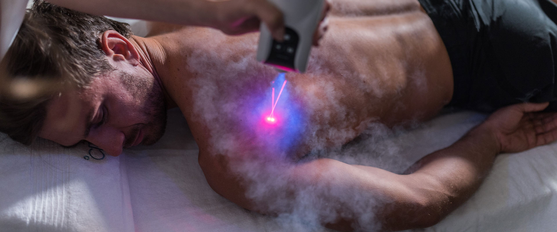 Ein Mann liegt entspannt auf einer Liege, während ein Lasergerät seinen Rücken bestrahlt.