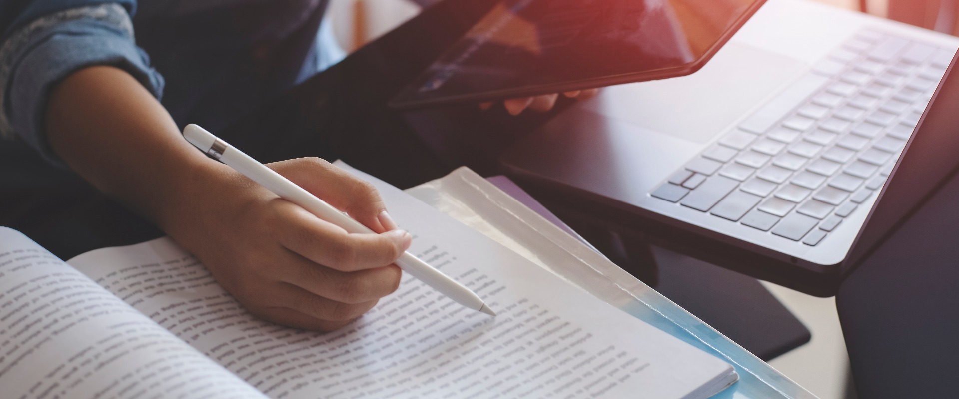 Young woman using digital tablet and work on laptop computer while reading book at home. Online education concept.